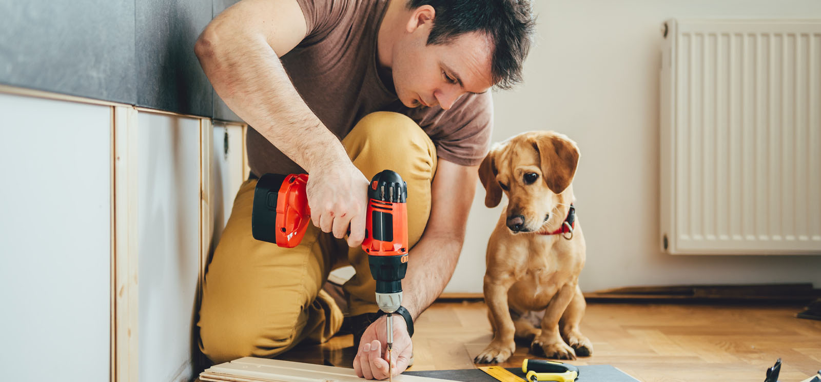 man using power tools while dog watches