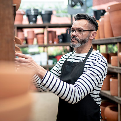 Business man working stacking pots on shelves.