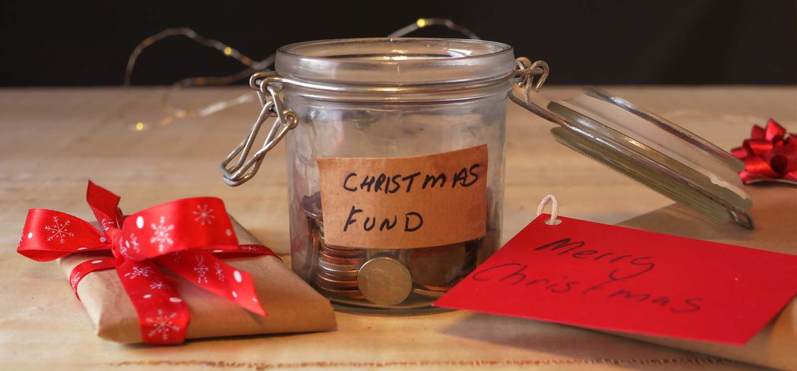 Christmas savings fund in glass jar to buy gifts. Small wrapped gift.
